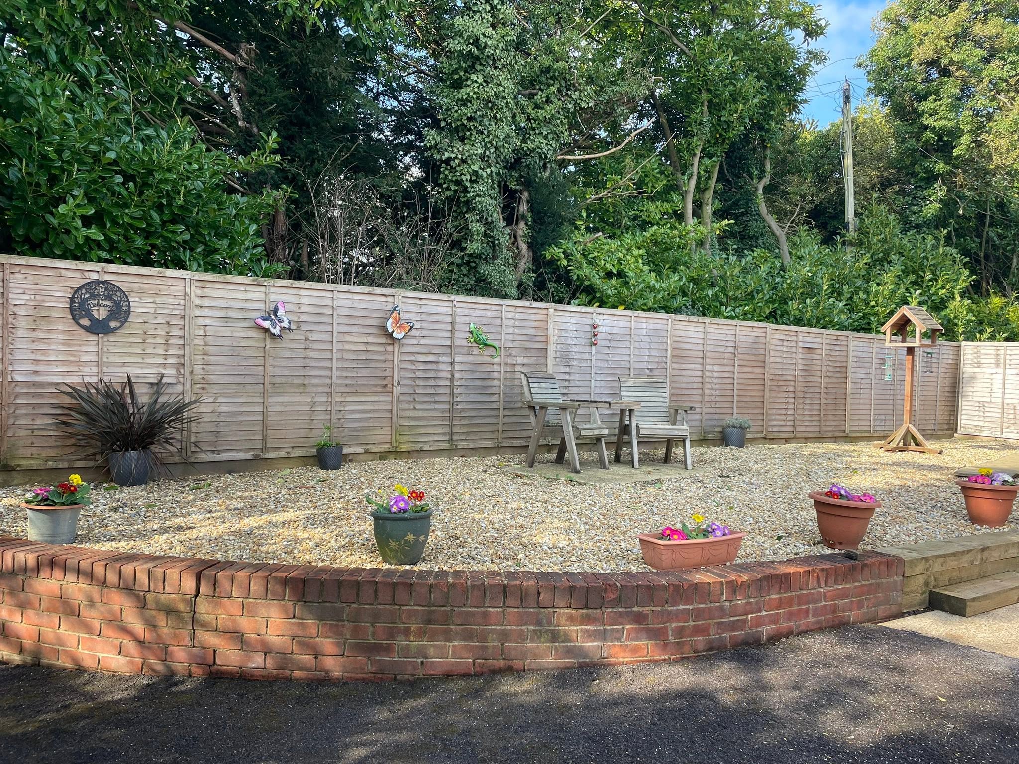The raised gravelled seating area, with a bench and pots of flowers